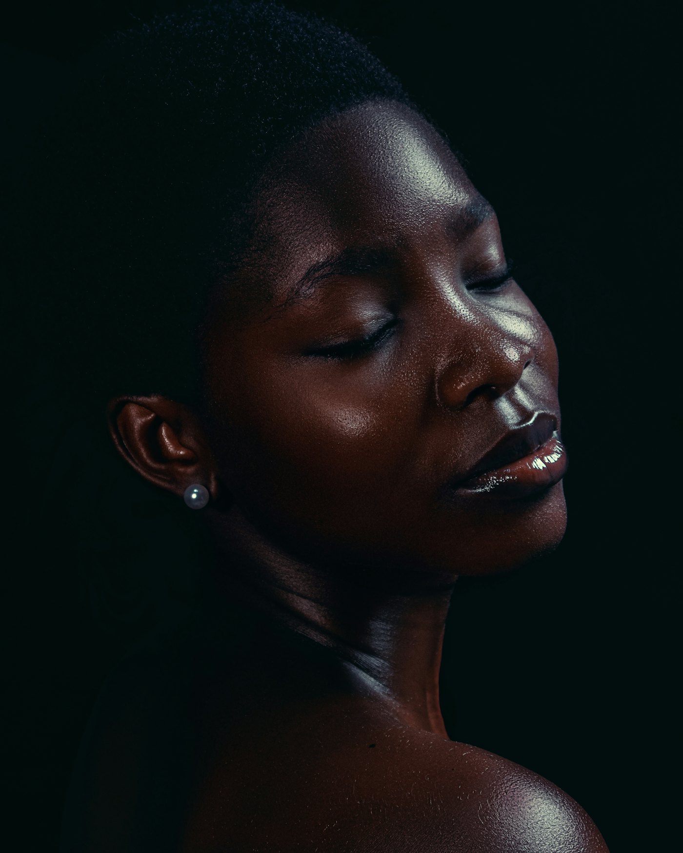 A woman with deep skin tone, eyes closed in soft light